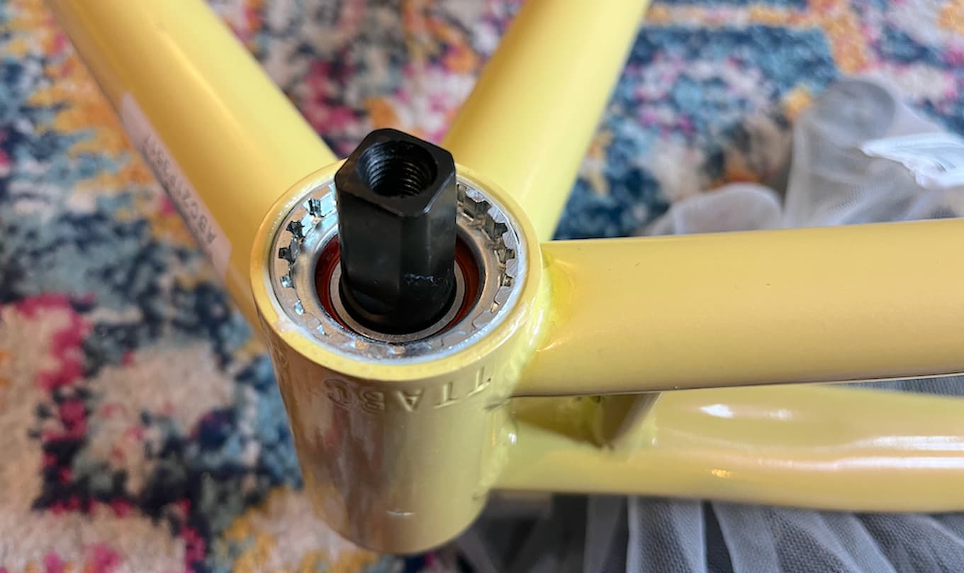 Bottom bracket inserted into a light yellow bicycle frame